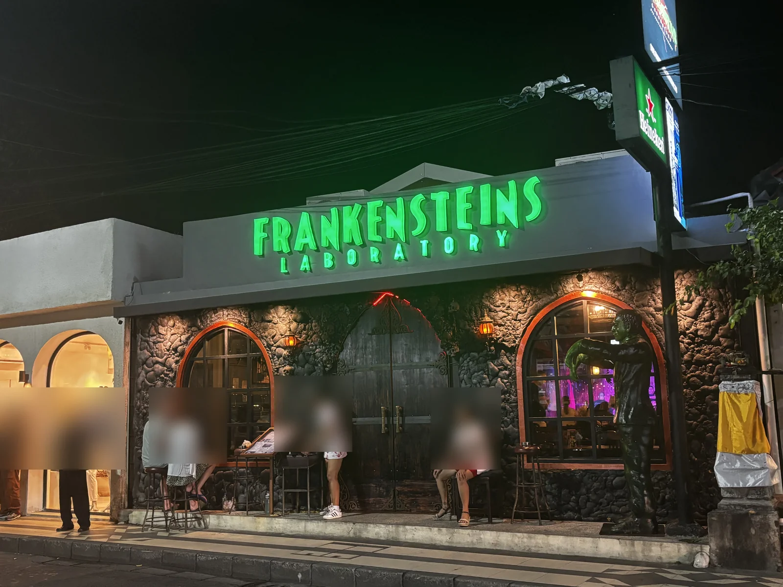 峇里島水明漾 Frankensteins Laboratory 餐酒館夜間完整店面，石造拱門、綠色科學怪人招牌與門口客人