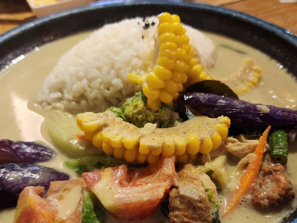 泰式青咖哩飯特寫，白飯配玉米筍、茄子、蝦子與時蔬，淋上濃稠咖哩醬汁