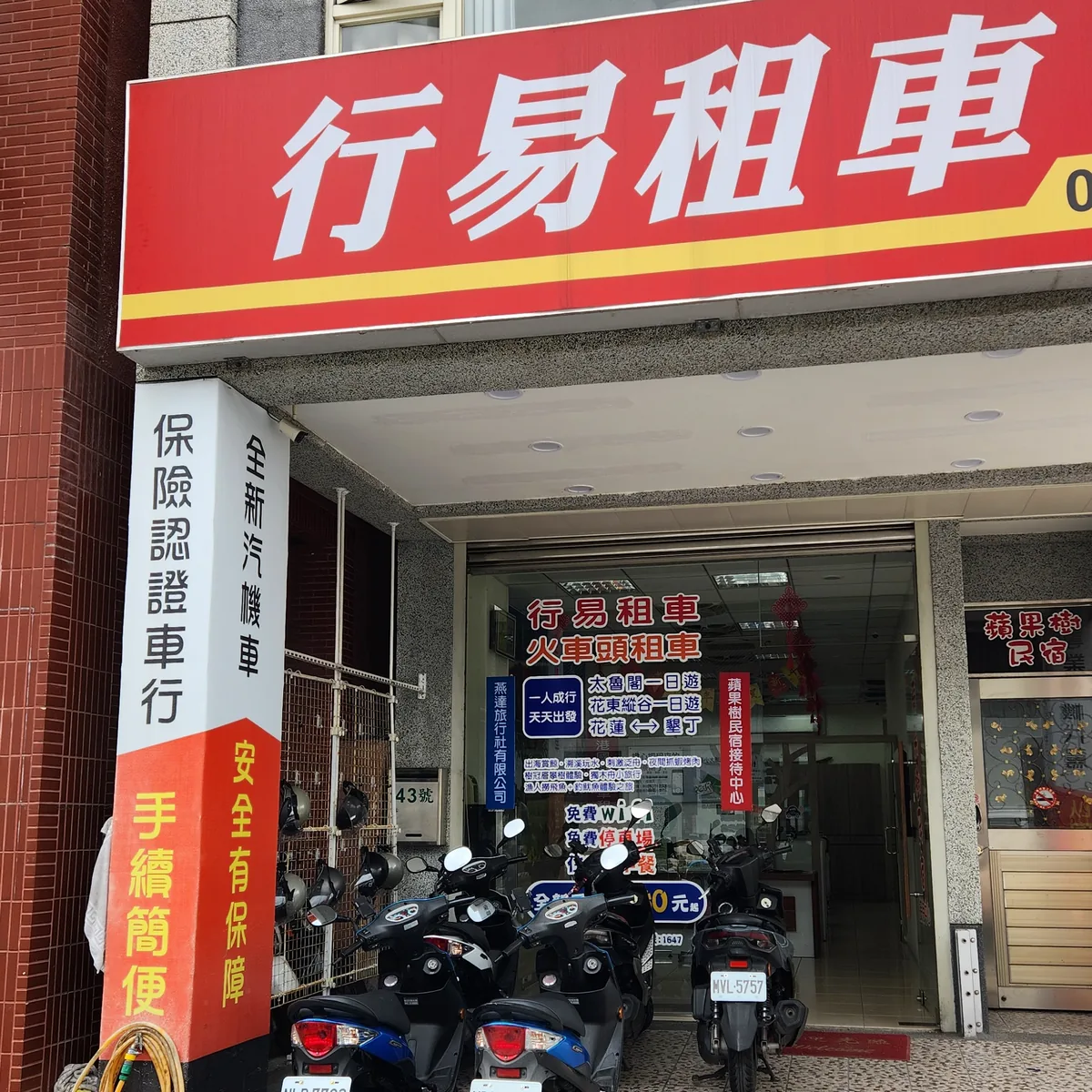 花蓮行易租車門市招牌與店面，紅底白字招牌寫著太魯閣一日遊、花東縱谷一日遊，門口停著多輛出租機車