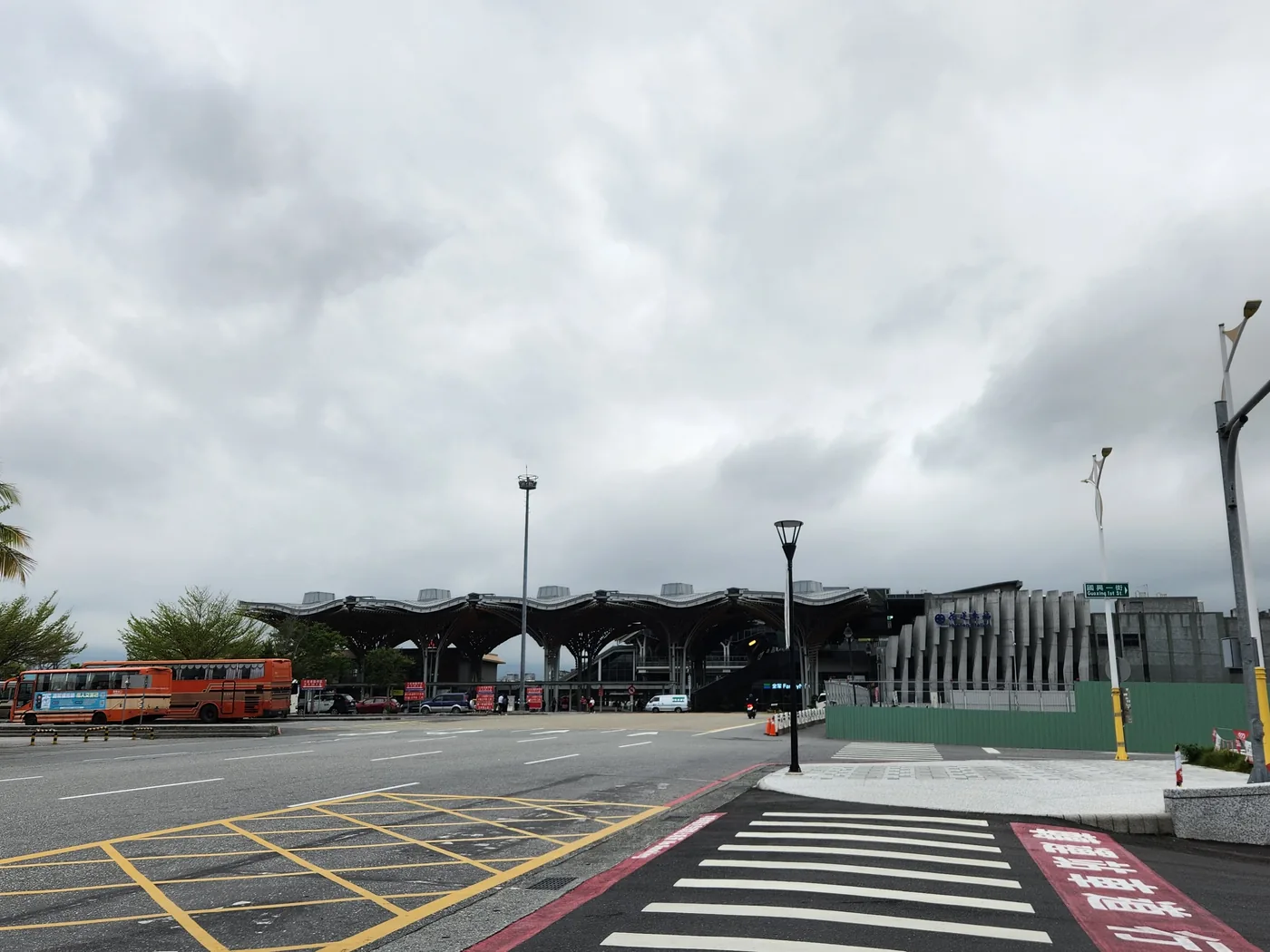 花蓮車站前廣場，弧形波浪屋頂建築，陰天多雲，一輛橘色公車停靠在站前車道
