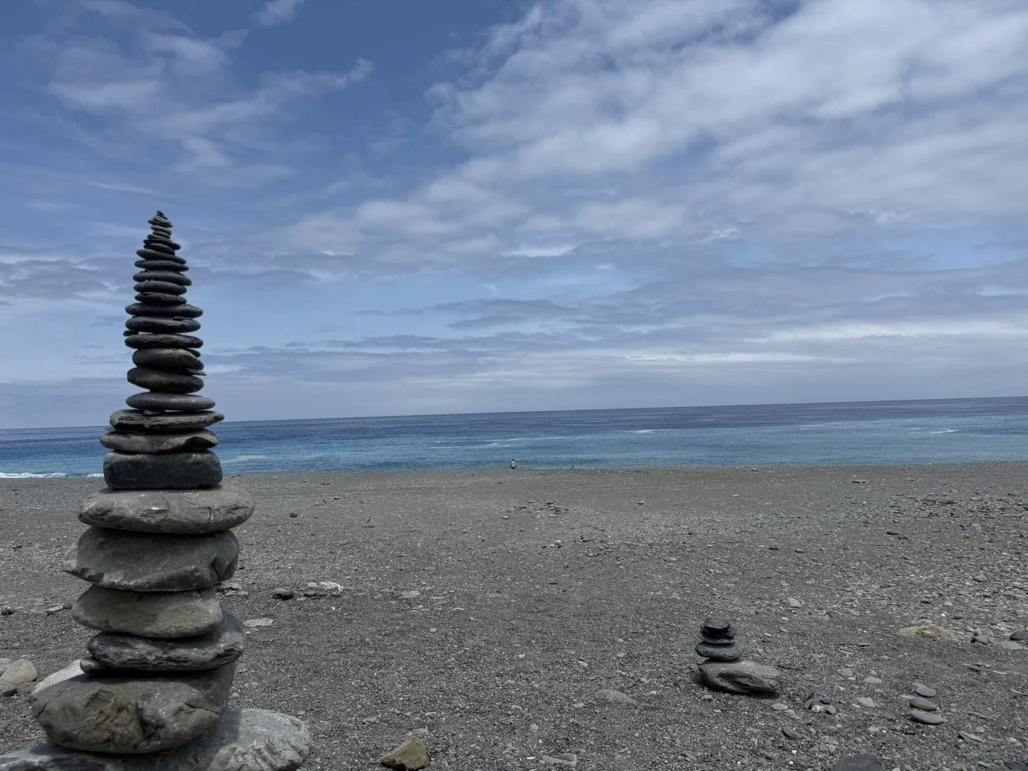 太麻里海邊礫石灘上旅人堆疊的石頭塔，背景是湛藍的太平洋海面