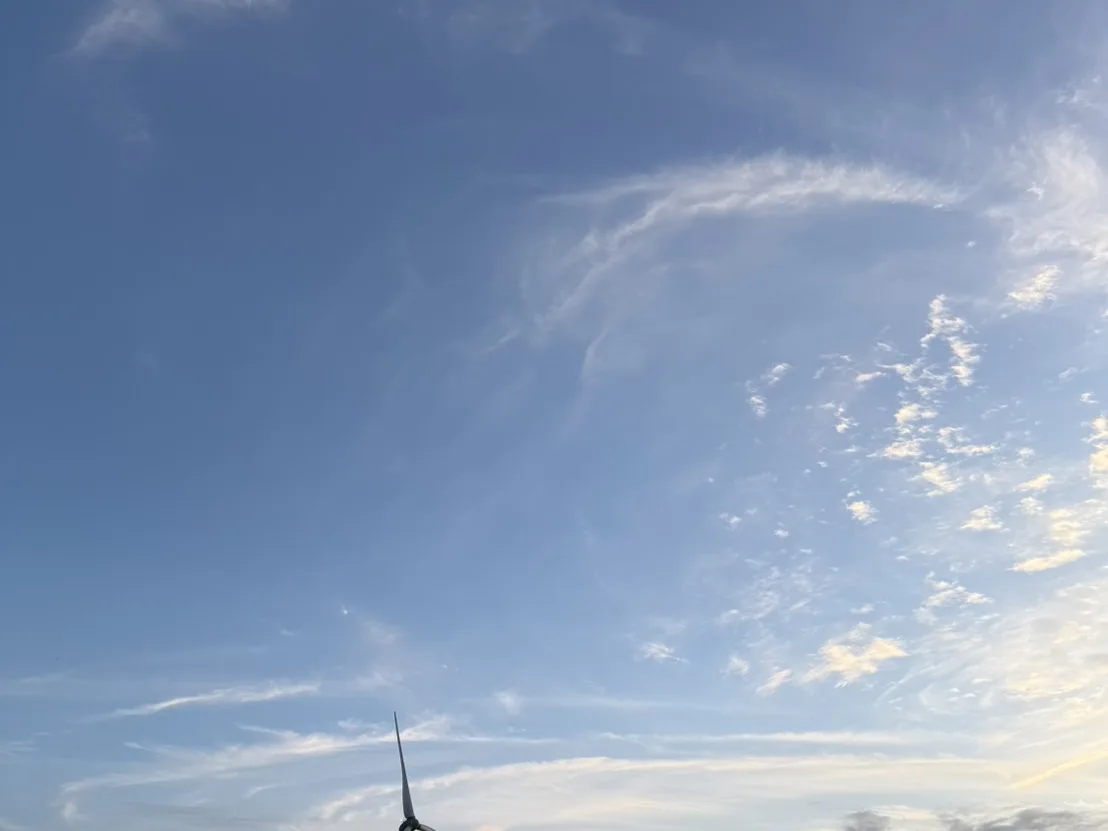 龍鳳漁港停泊的漁船與遠方離岸風力發電機，藍天白雲映照在水面上