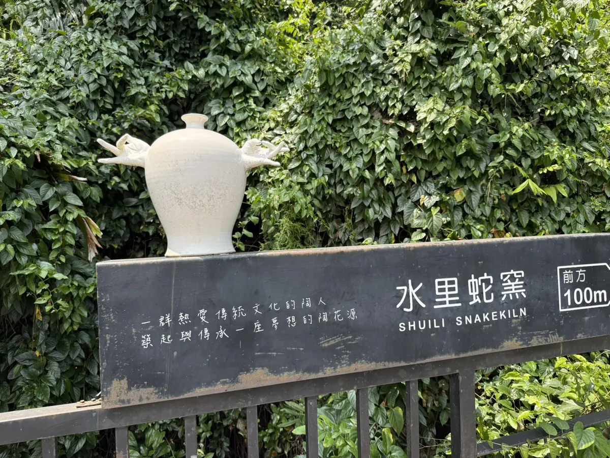 水里蛇窯路邊的黑色指示牌，寫著水里蛇窯前方 100m，牌上放著白色陶甕