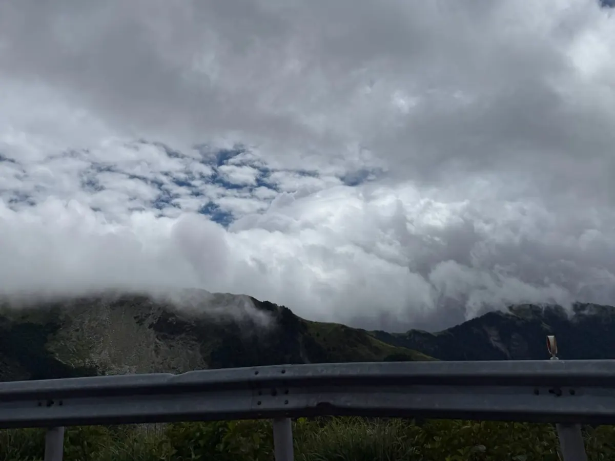 武陵農場沿線山路護欄外的雲海，雲層從山谷翻上山稜線