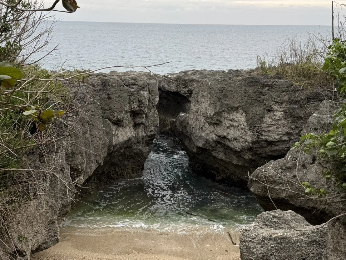 小琉球礁岩海岸邊一處隱藏的沙灘小海灣，兩側天然礁岩形成拱門狀