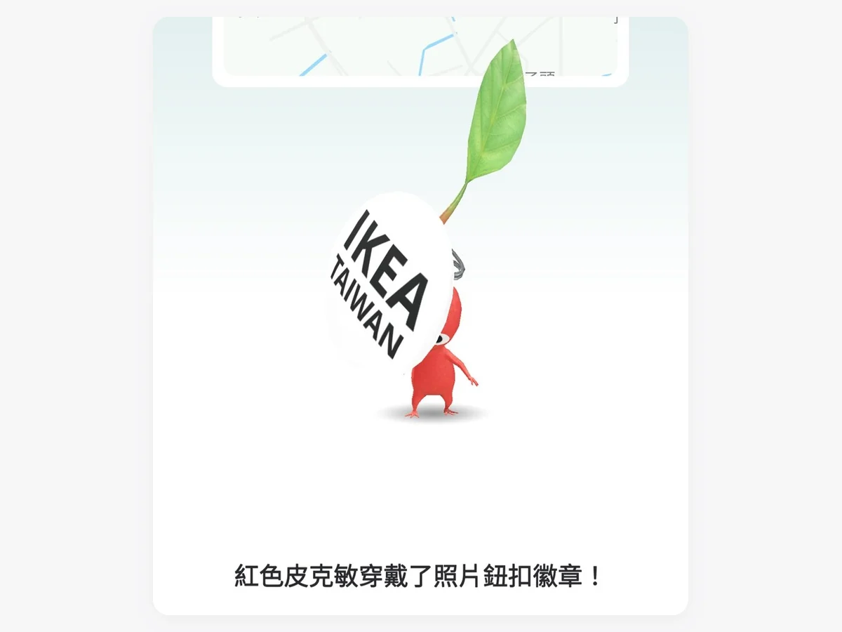 《Pikmin Bloom》畫面：紅色皮克敏背著印有 IKEA TAIWAN 的白色圓形徽章，下方文字寫著「紅色皮克敏穿戴了照片鈕扣徽章！」