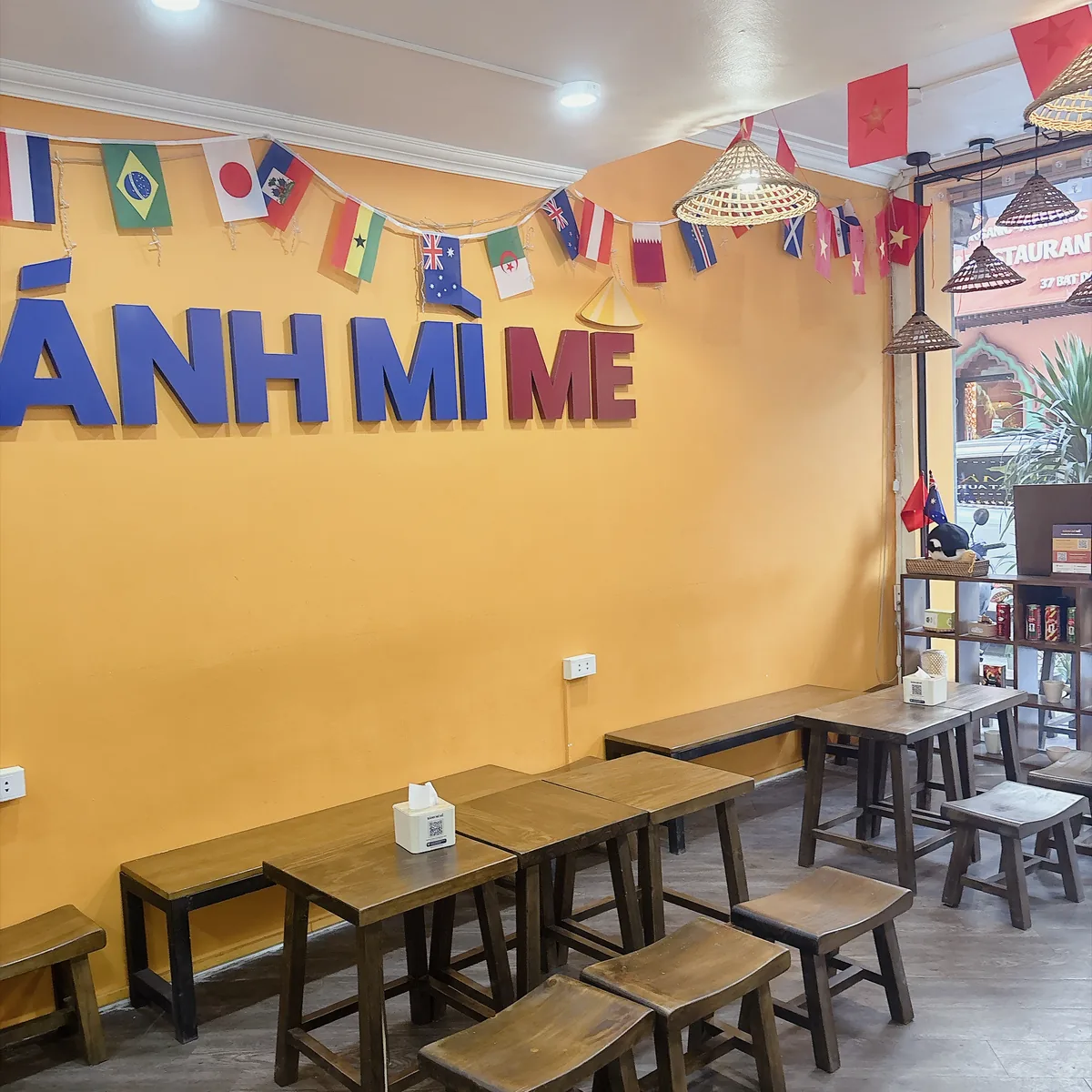 河內 Bánh Mì 25 店內，黃色牆面掛著各國國旗與店名字樣