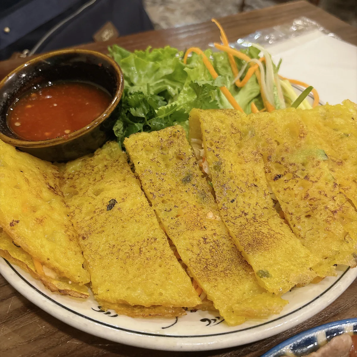 切成長條的越南煎餅擺在盤上，旁邊配生菜與一碗沾醬