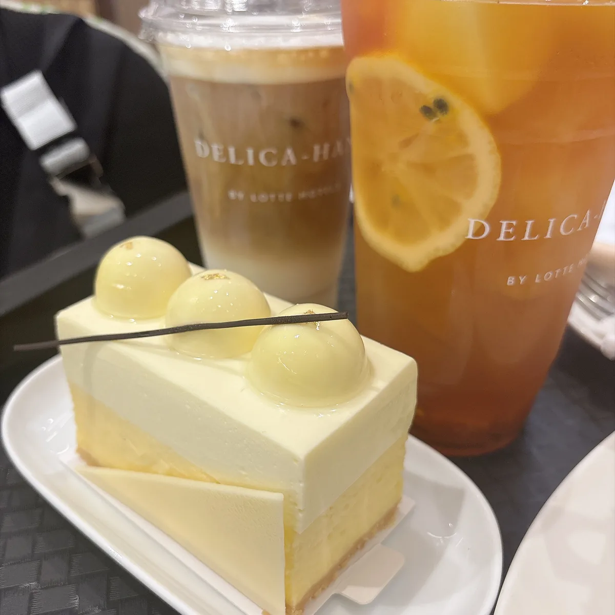 Delica-Hans 的方形蛋糕與兩杯飲料放在店內桌上