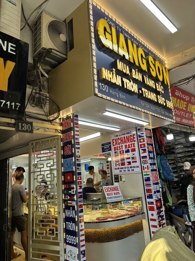 河內一間金銀首飾店，門口貼滿各國國旗的匯率牌，寫著 EXCHANGE BEST RATE