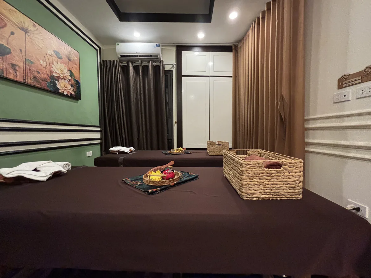 河內 SPA 店的按摩床，鋪著深色床單，旁邊放著置物籃