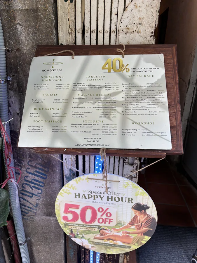 河內 SPA 店門口的立牌價目表，下方掛著 HAPPY HOUR 50% OFF 的圓形吊牌