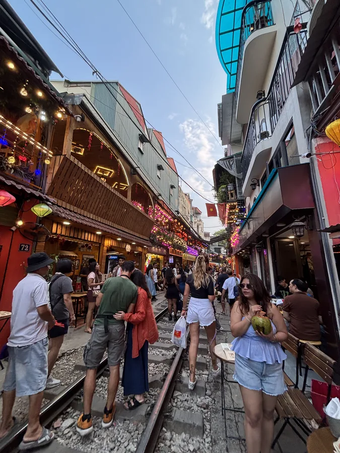 河內火車街，鐵軌兩側坐滿旅客，店家沿著軌道擺出座位