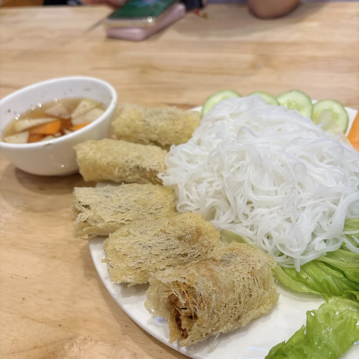 VIỆT QUÁN 的酥炸春捲配米線與生菜，旁邊一碗沾醬