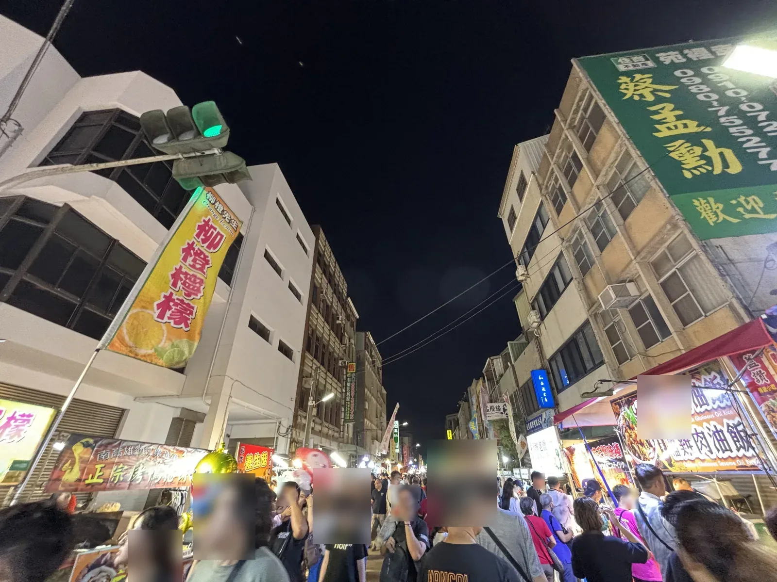 苗栗苑裡鬼門關夜市入夜後的街景，柳橙檸檬與鴨肉油飯等攤販招牌亮起，街上滿是逛夜市的人
